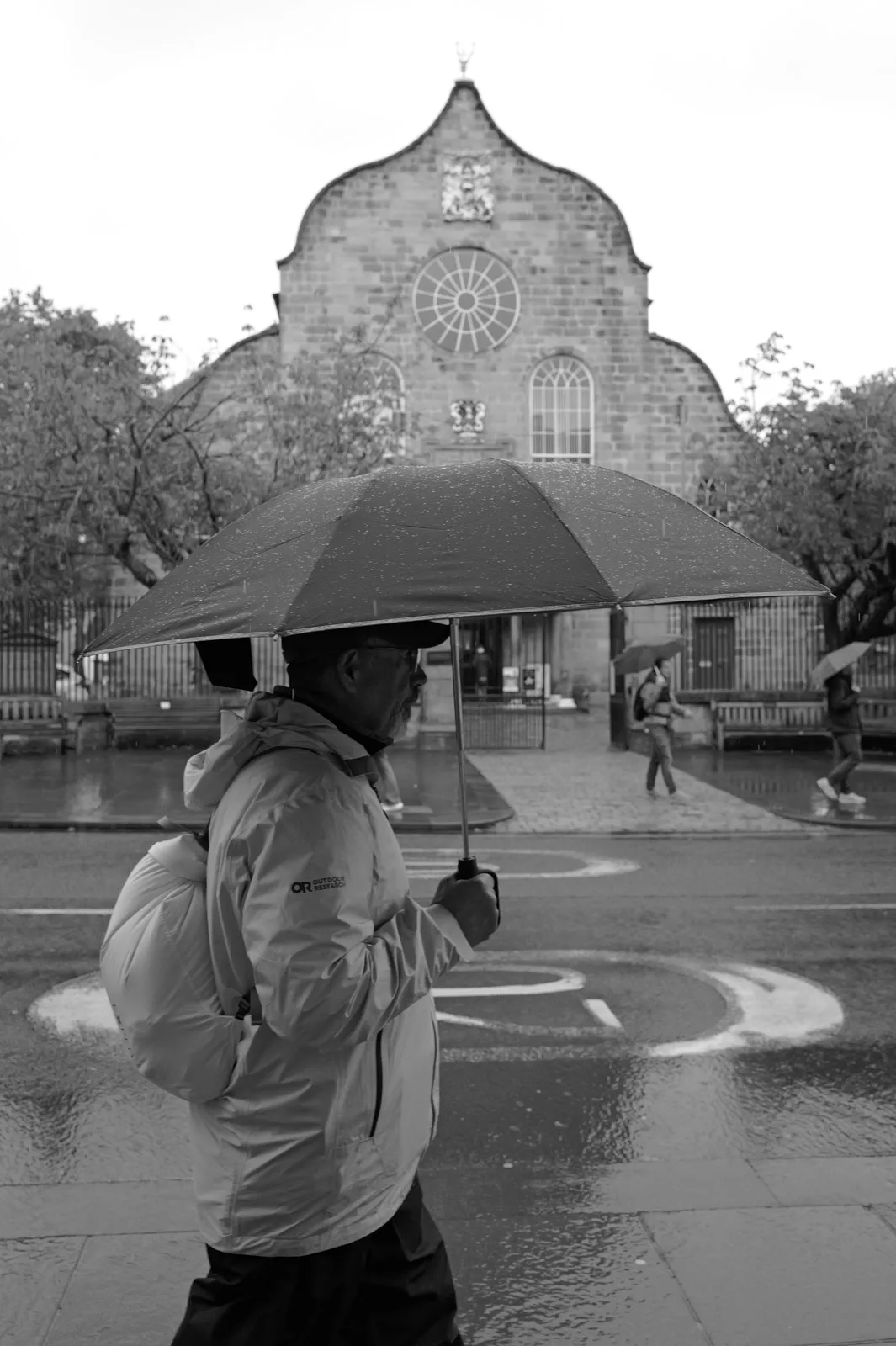 Man under an umbrella in front of a church on a rainy day, Edinburgh
