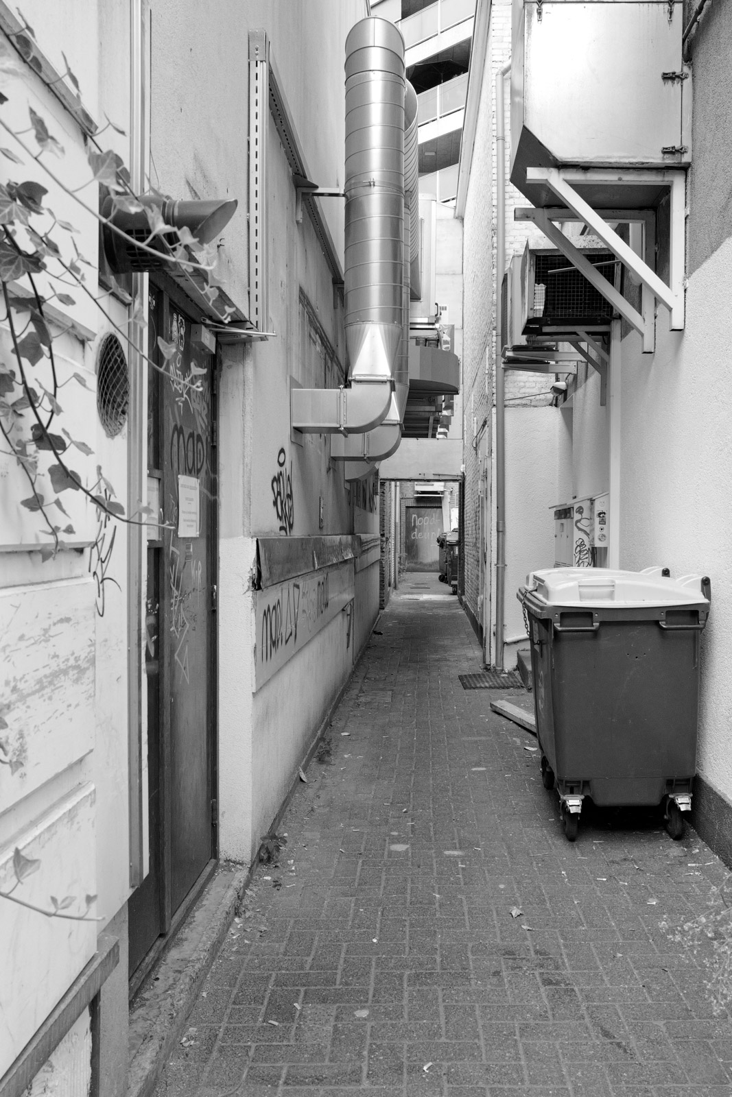 Ruelle de service entre des batiments, poubelles et tuyauteries, Eindhoven