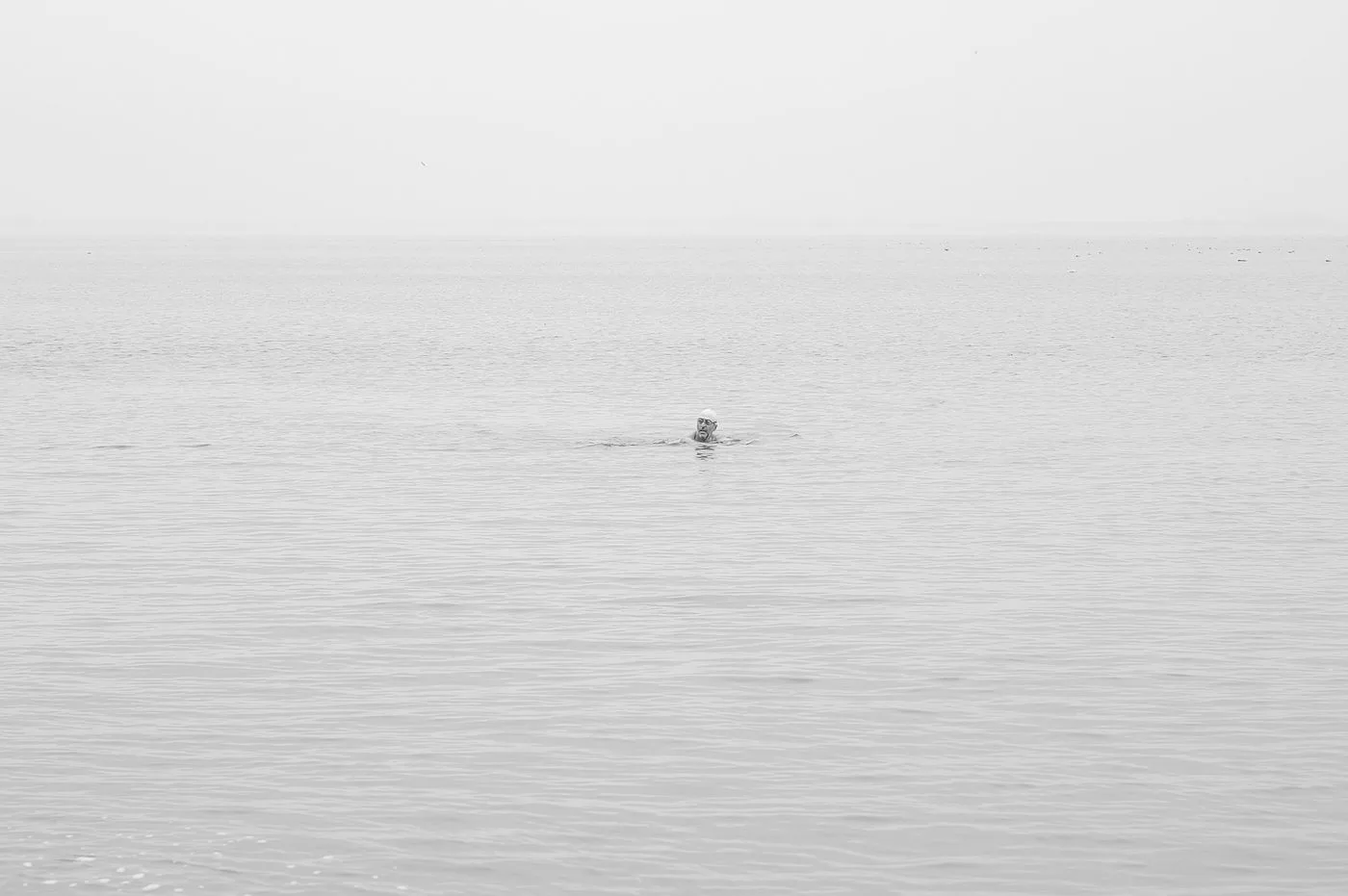 Un nageur seul au loin sur une mer lisse, Coney Island, New York