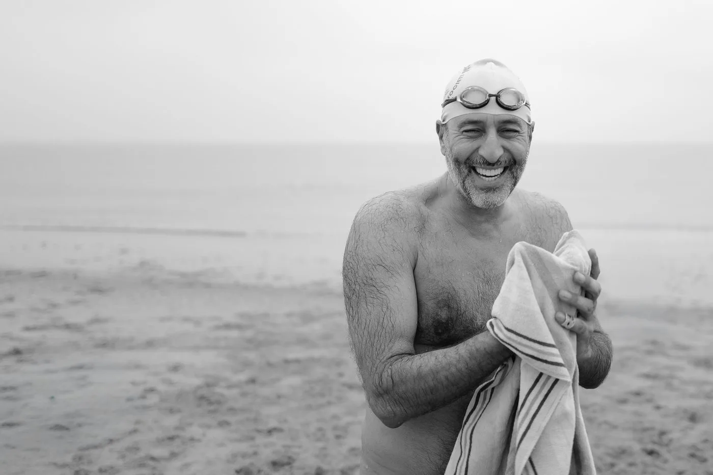Un nageur en bonnet éclate de rire, serviette serrée contre lui, Coney Island, New York