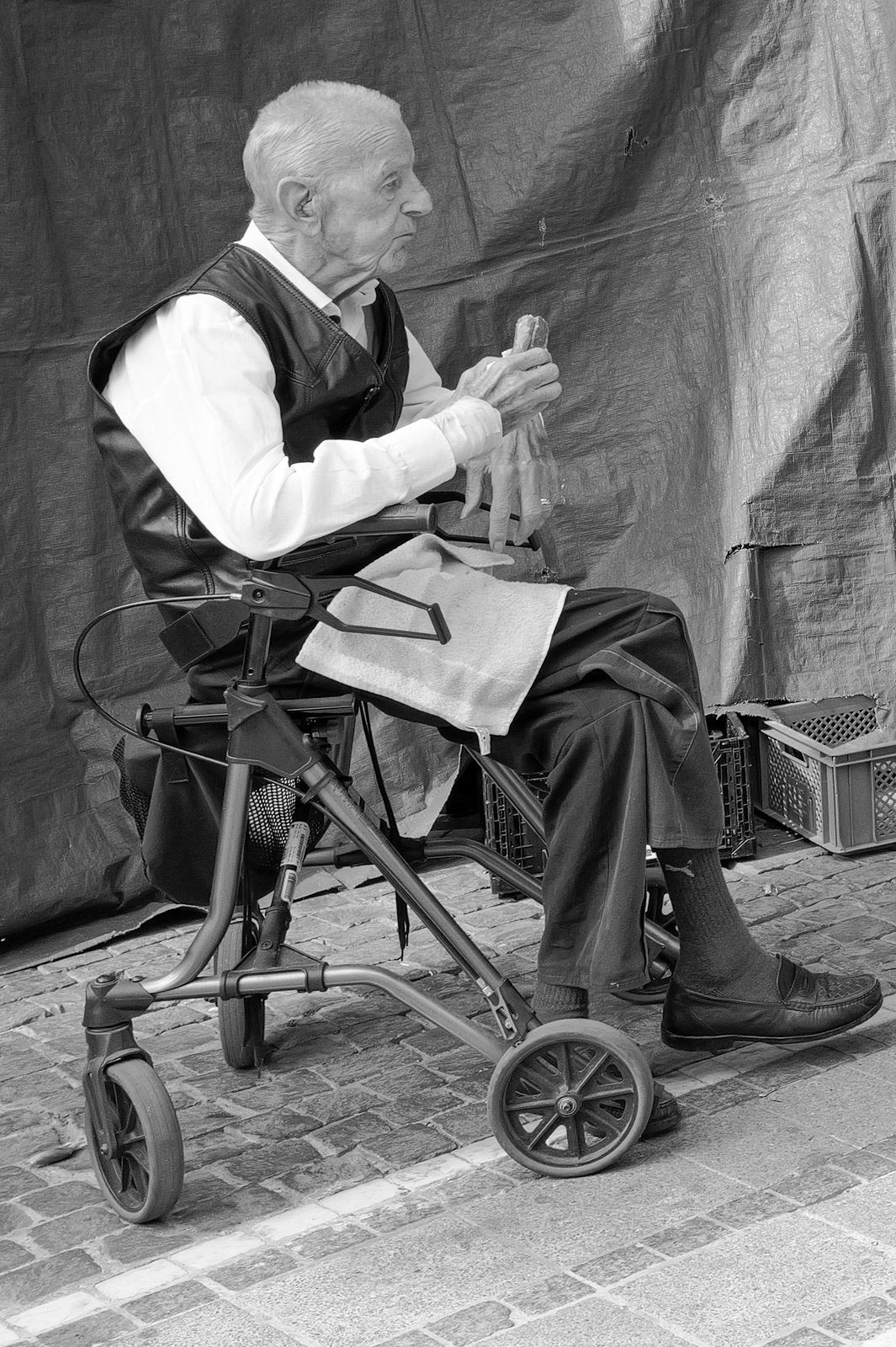 Homme age assis sur un deambulateur sur les paves, Francfort