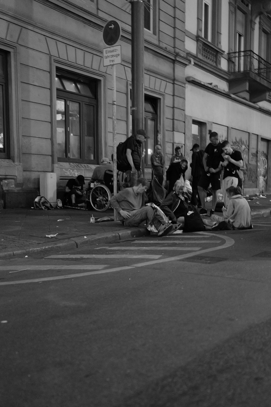 Groupe de personnes assises sur un trottoir pres d'un immeuble, Francfort
