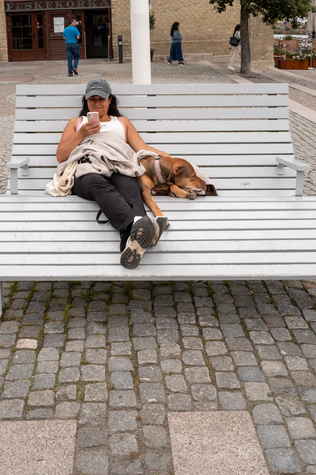 A woman lying on a big white bench with her dog, Gothenburg