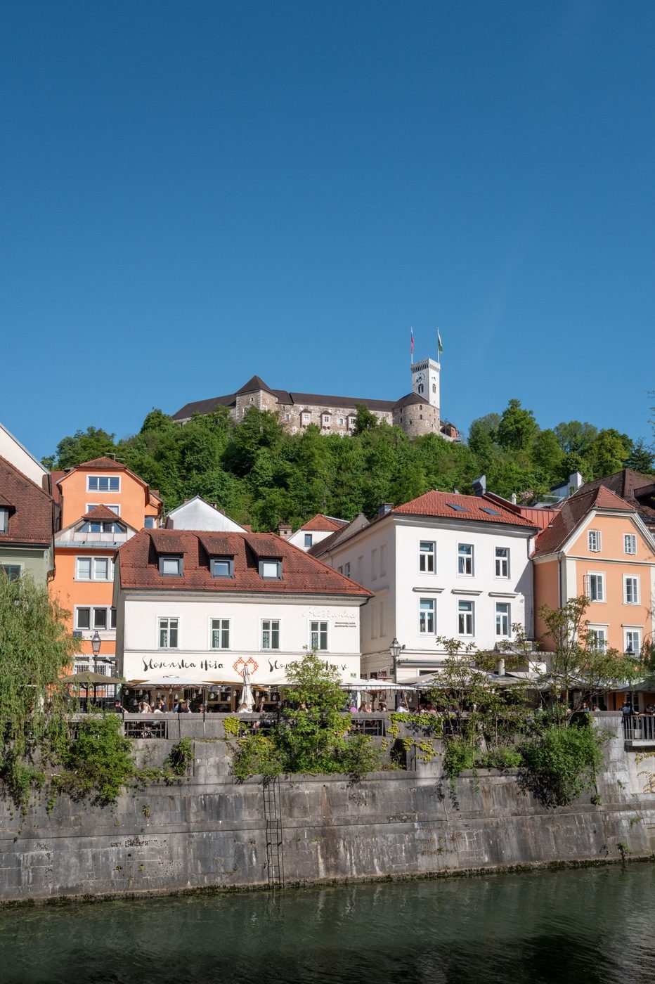 Castle perched above the pastel facades along the riverside, Ljubljana