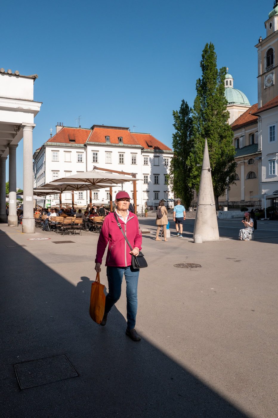 Woman in a pink jacket crossing the square in front of the cathedral dome, Ljubljana
