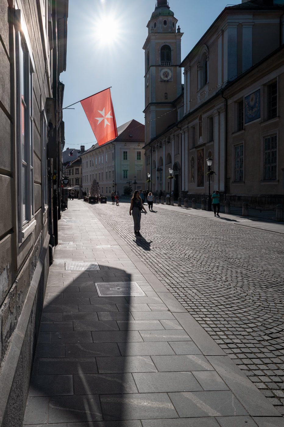 Maltese cross flag flying above the cobbled street, Ljubljana