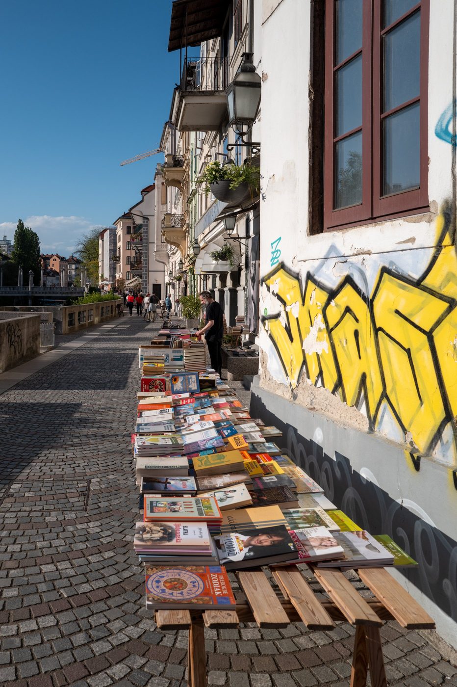 Secondhand book stalls near a graffiti-covered wall, Ljubljana