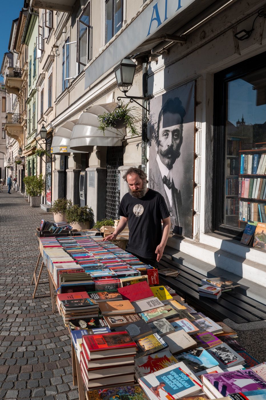 Bookseller arranging his books in front of an old poster, Ljubljana