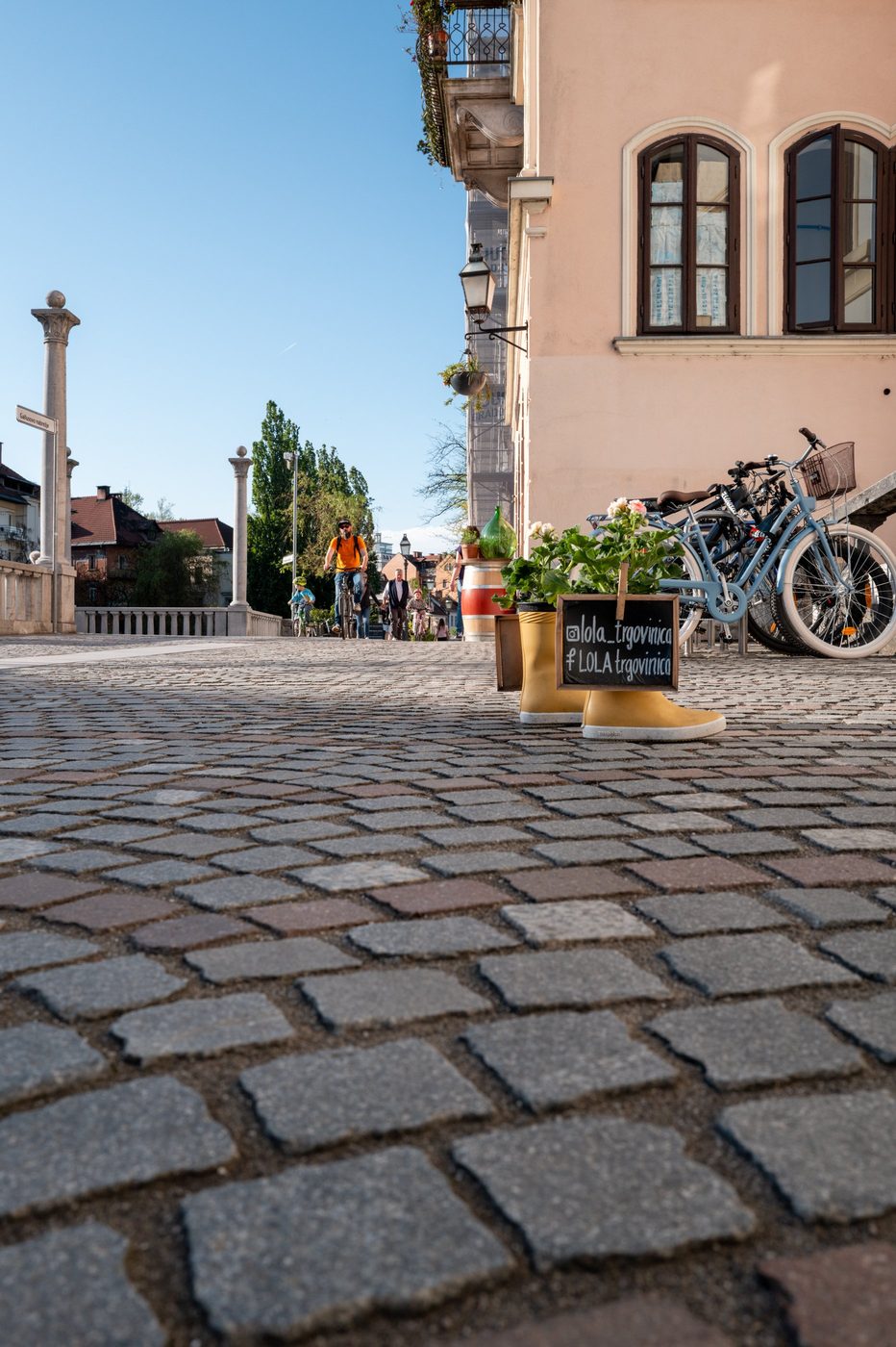 Yellow boots used as a flower pot in front of a pink facade, Ljubljana