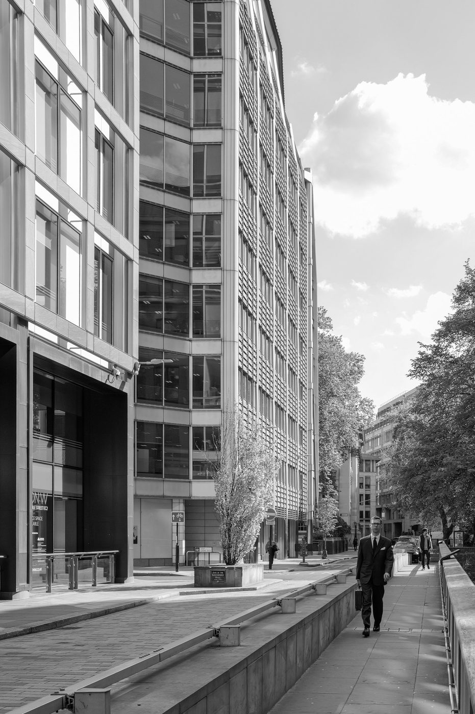 Businessman in a suit walking alone between glass office towers, London