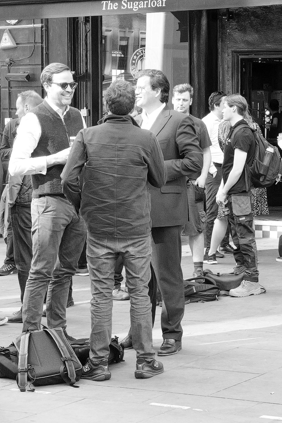 Group of men deep in conversation outside The Sugarloaf pub, London