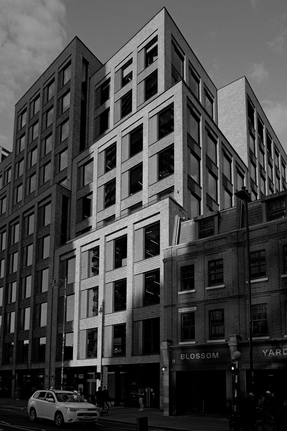 New brick office building contrasting with the old facade next door, London