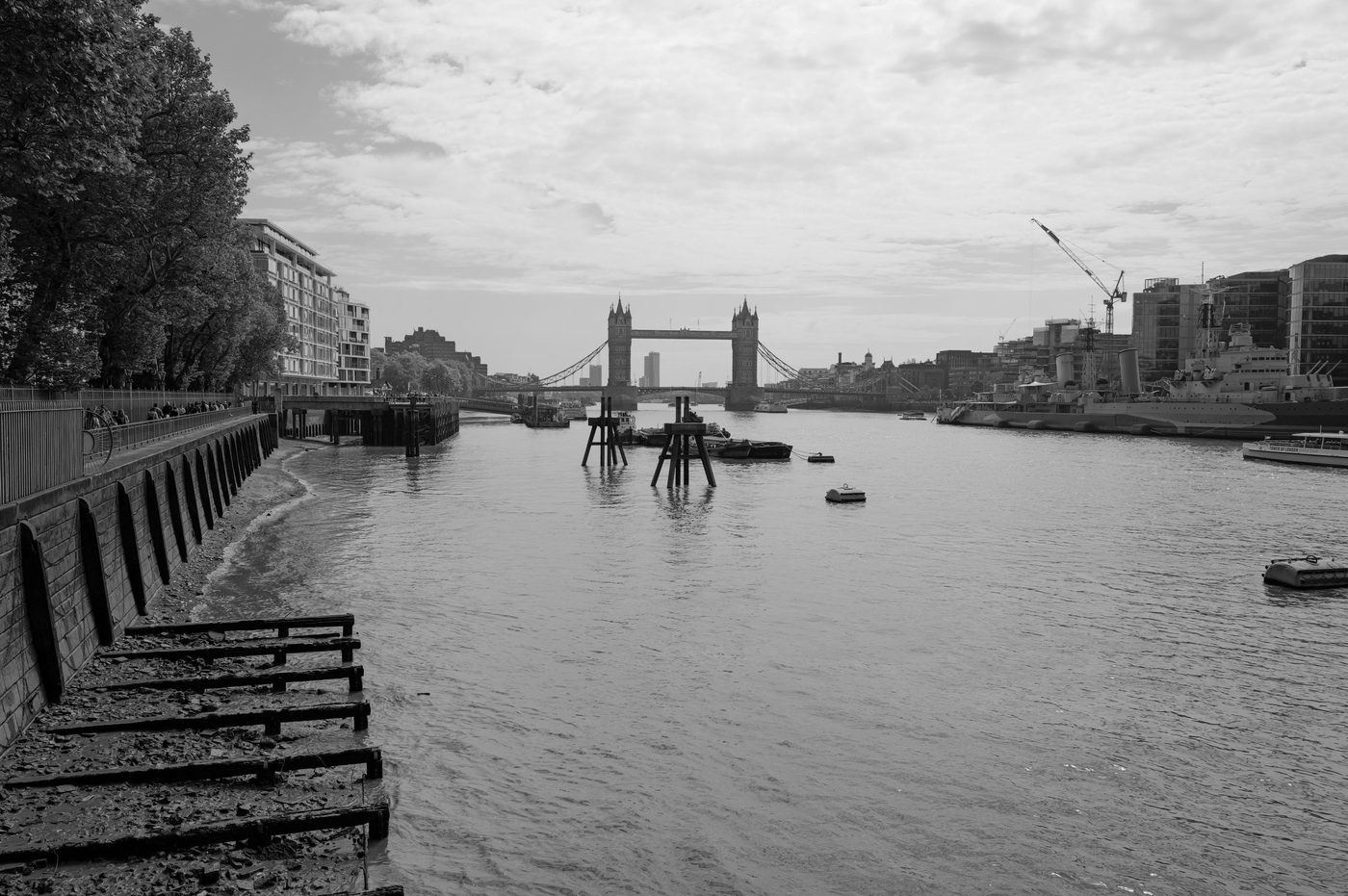 The Thames at low tide with Tower Bridge and a warship on the horizon, London