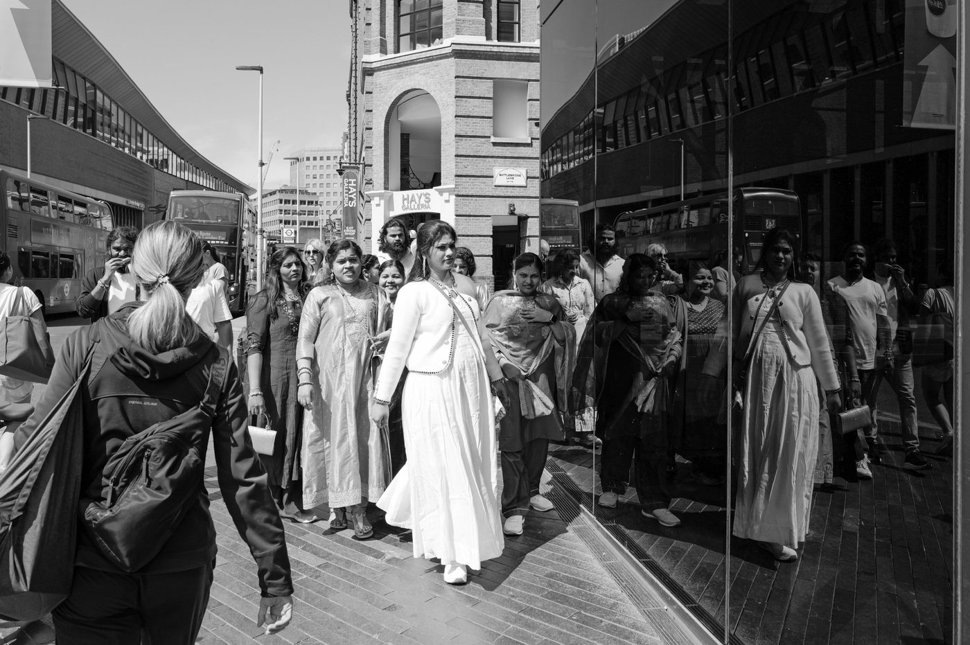 Group of women in colourful traditional dress reflected in a shop window, London