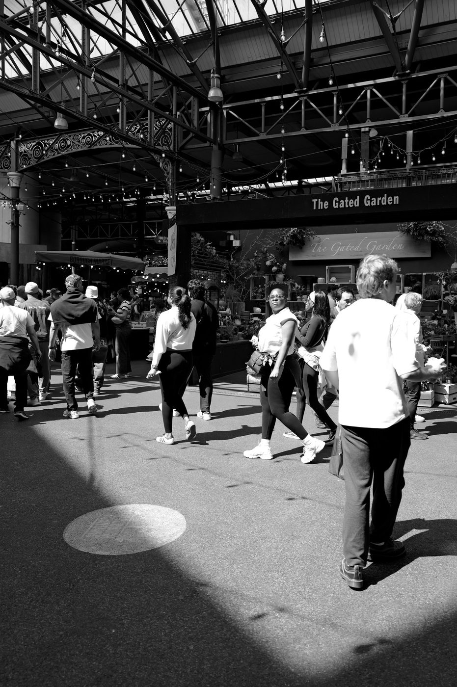 Crowd of visitors strolling under the glass roof of a covered market hall, London
