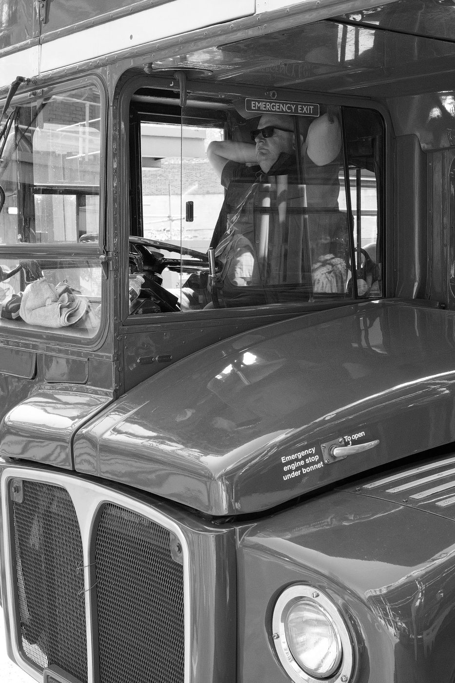 Driver of a vintage double-decker bus leaning on his cab window, London