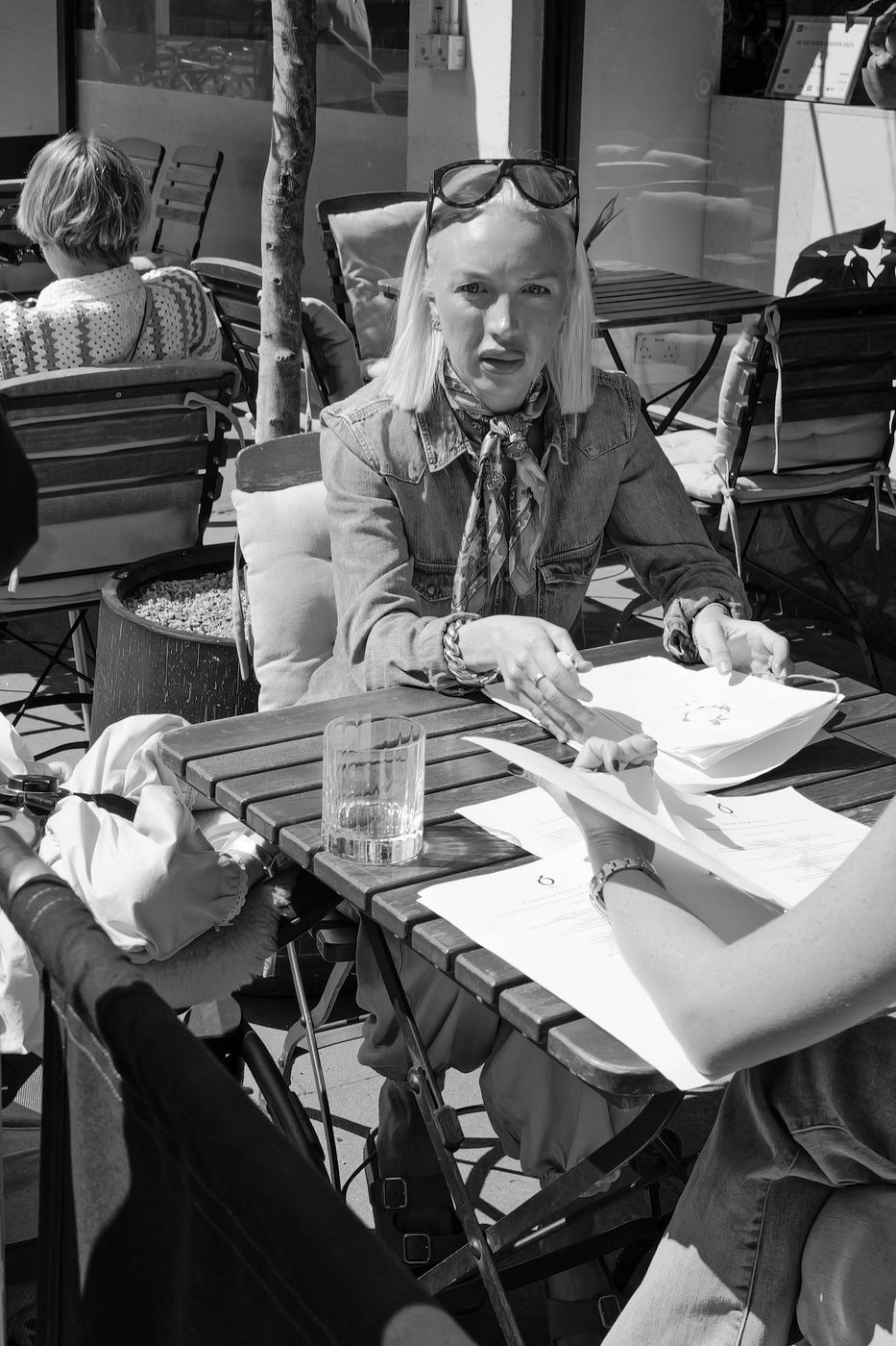 Blonde woman looking at menus on a terrace with her companion, London