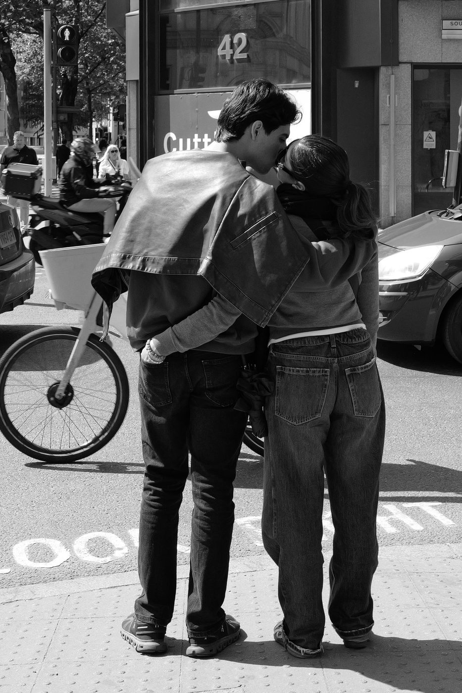 Young couple kissing on the pavement, bicycle and traffic in the background, London