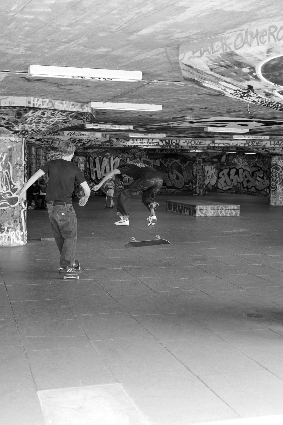 Two skaters chaining tricks together in the graffiti-covered skatepark, London
