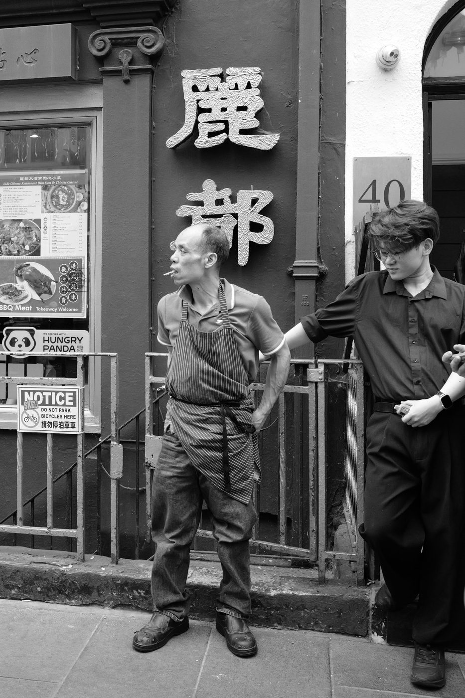Cook in a striped apron smoking a cigarette outside his Chinese restaurant, London