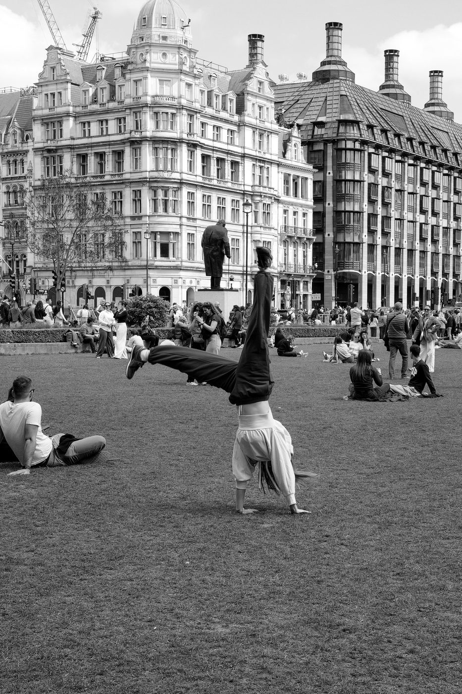 A street performer balancing on his hands in front of the buildings of Parliament Square, London