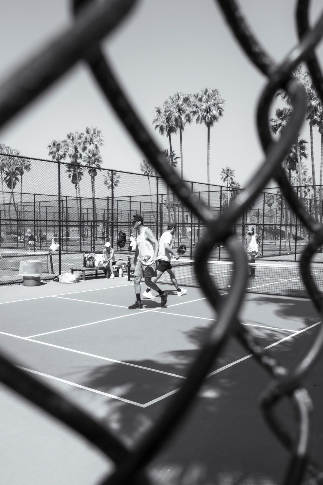 Tennis players seen through a chain-link fence, Los Angeles