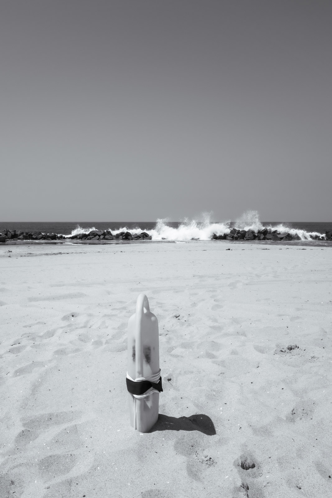 Broken post planted in the sand facing the ocean, Los Angeles