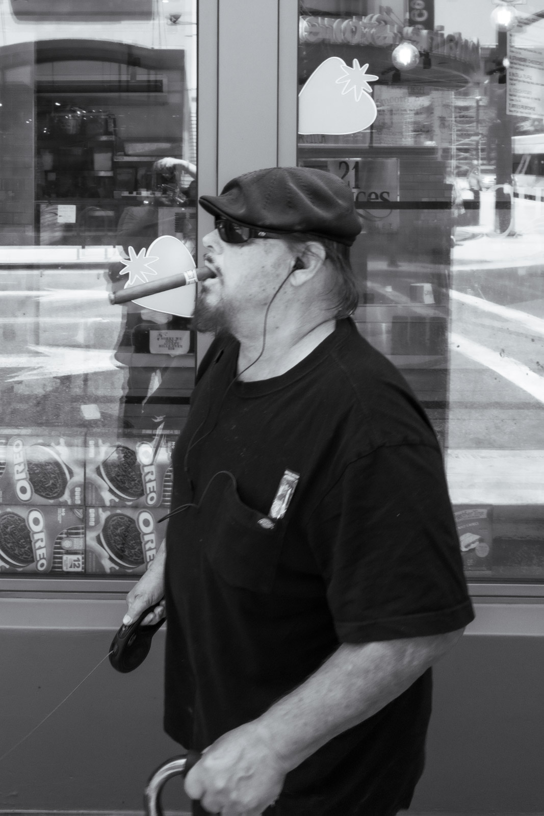 Older man in a flat cap eating in the street, reflections in a shop window, Los Angeles
