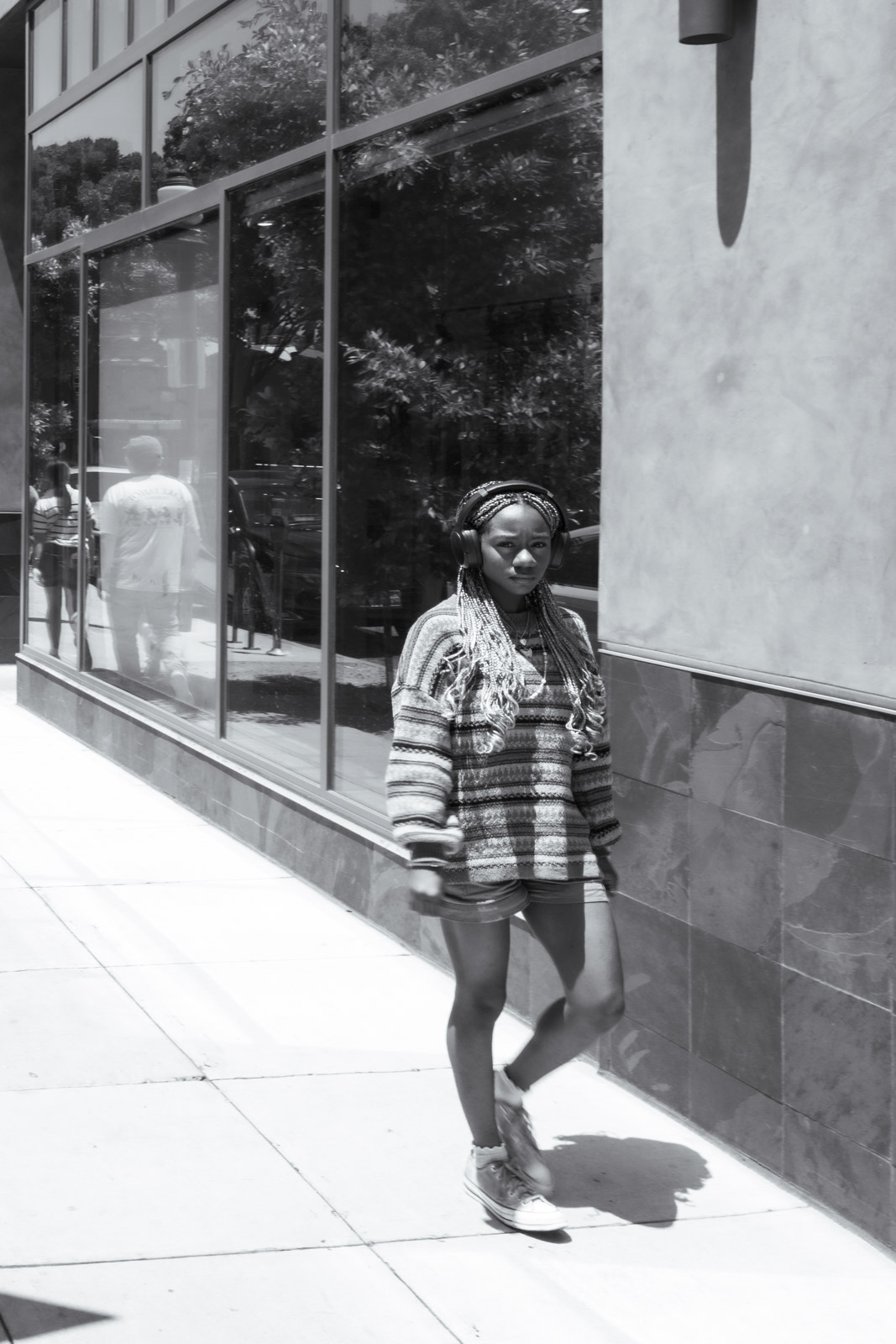 Woman crossing a sidewalk in front of shop windows, Los Angeles
