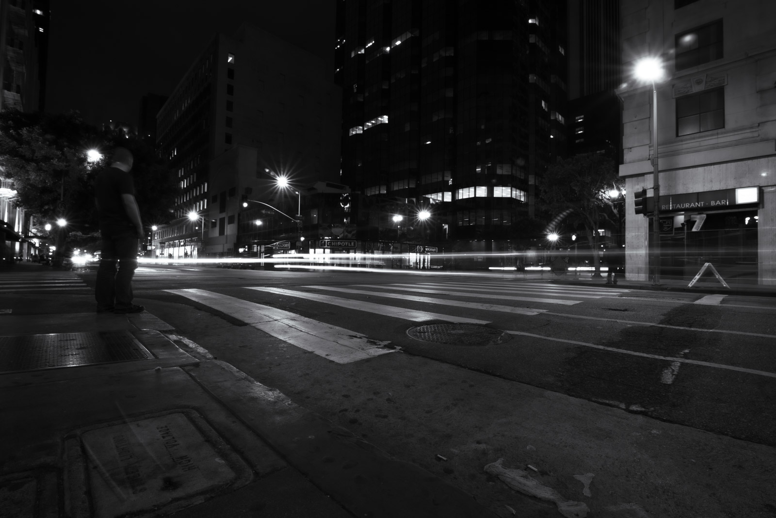 Empty nighttime street with headlight trails, buildings in the background, Los Angeles