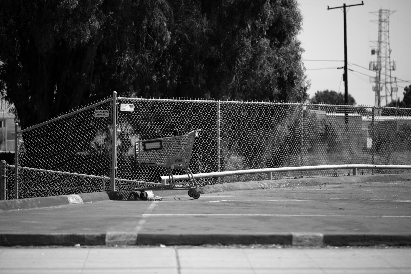 Skateboard locked to a chain-link fence, sports court in the background, Los Angeles
