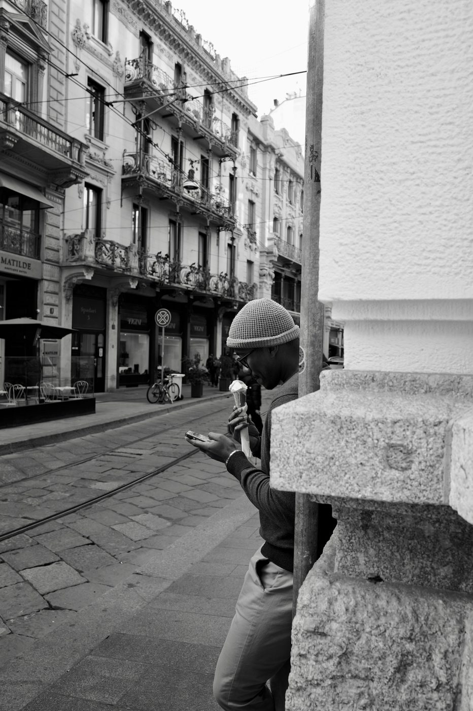 Man in a beanie enjoying an ice cream while checking his phone, Milan