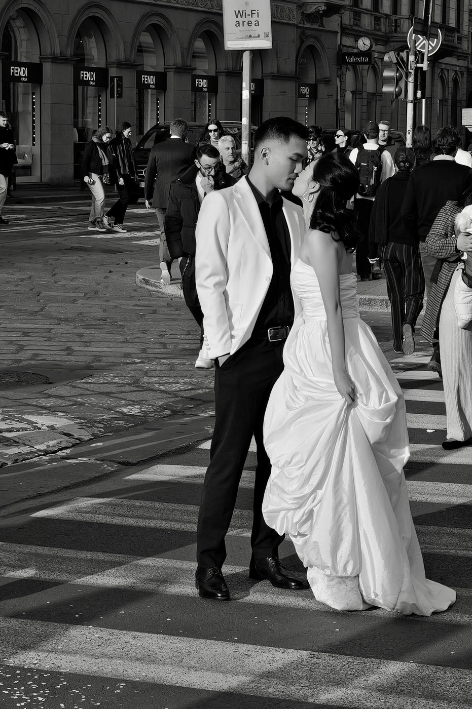 Newlyweds kissing on a pedestrian crossing amid the crowd, Milan