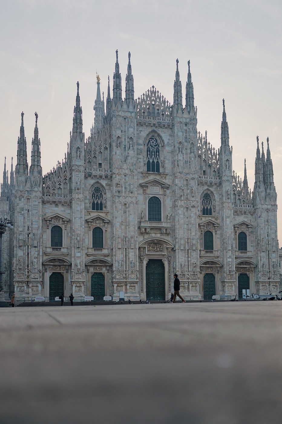Gothic facade of the Duomo cathedral, a lone silhouette in the early morning, Milan