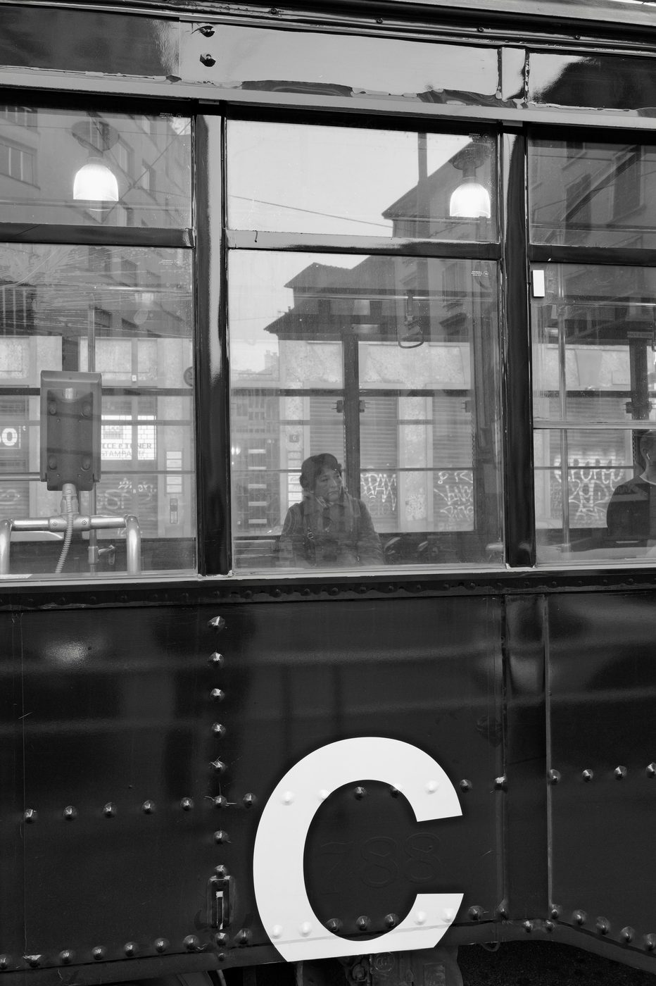 Passenger sitting in an old tram, the street reflected through the window, Milan
