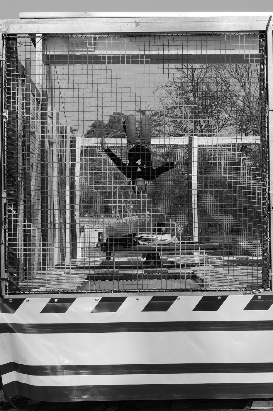 A man does a handstand on a caged elastic trampoline, Milan
