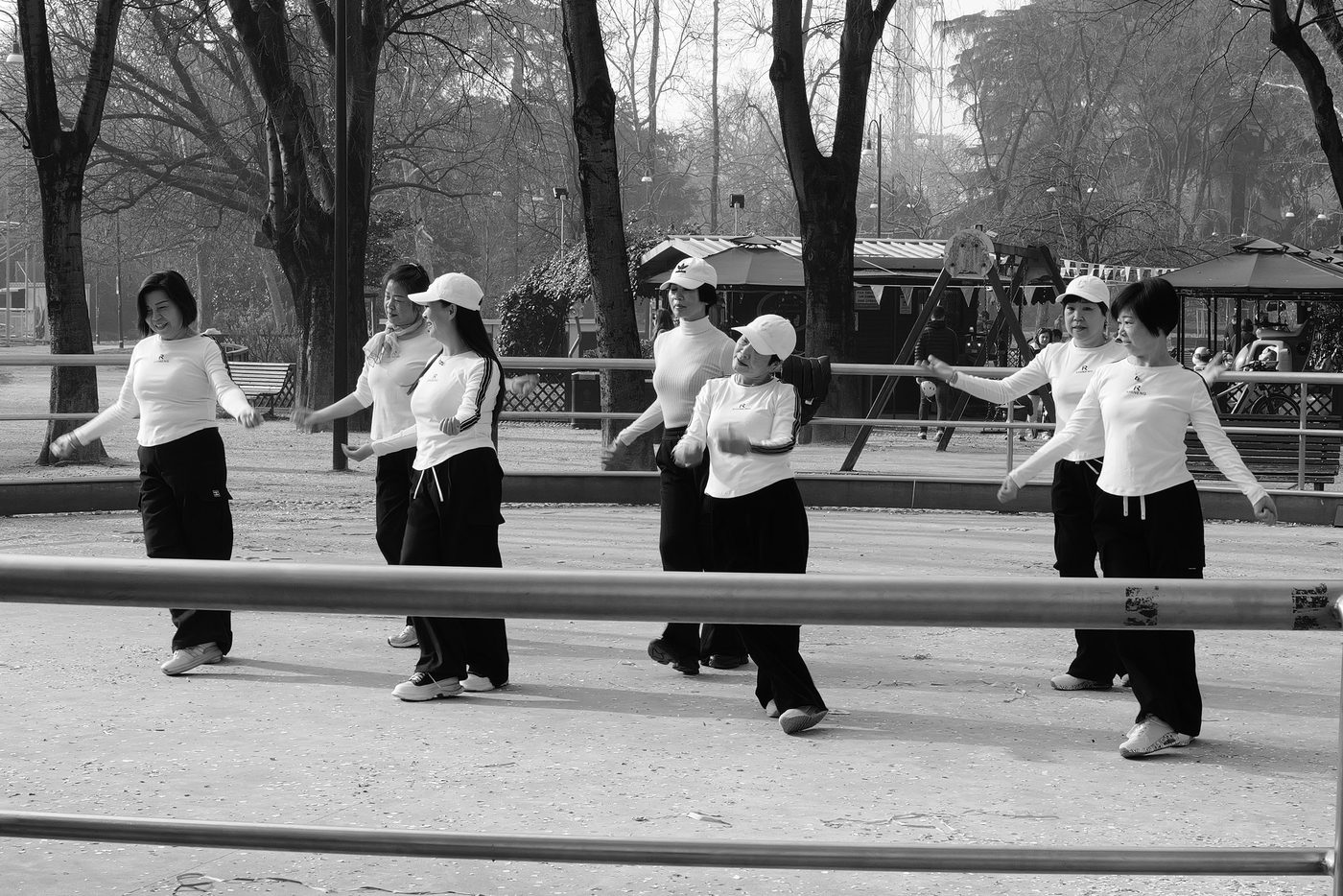 Group of women in matching outfits performing a dance routine in a park, Milan