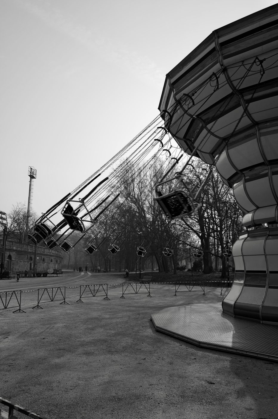 Swing-ride chairs tilted mid-turn above a park, Milan