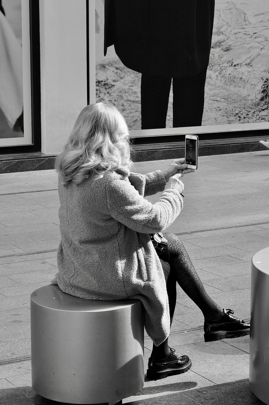 Curly-haired woman taking a selfie while sitting on a metal stool, Milan