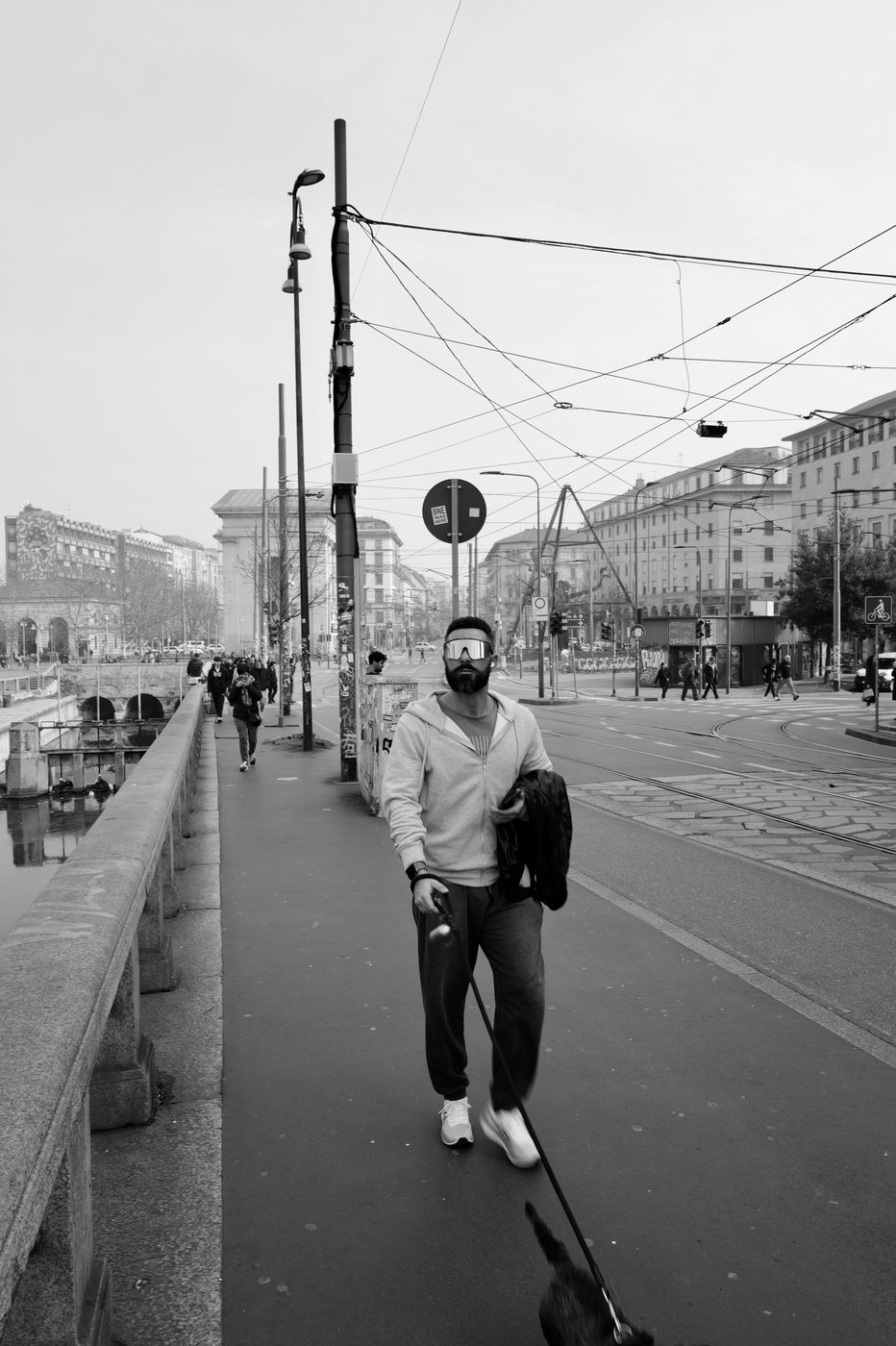 Bearded man in mirrored sunglasses walking his dog along the canal, Milan