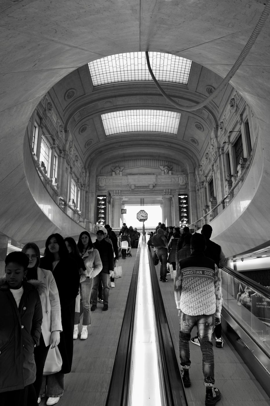 Circular moving walkway under the vaulted glass roof of the central station, crowd of travellers, Milan