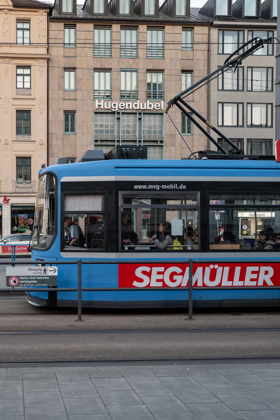 Blue Segmüller tram passing in front of the Hugendubel bookshop façade, Munich