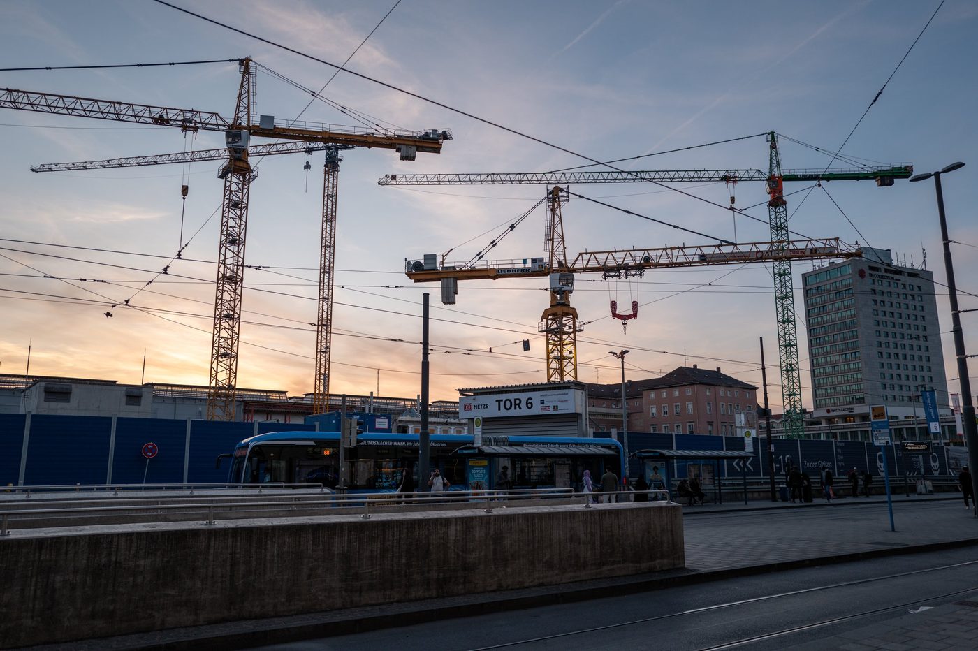 Construction cranes silhouetted against a dusk sky near the tram tracks, Munich