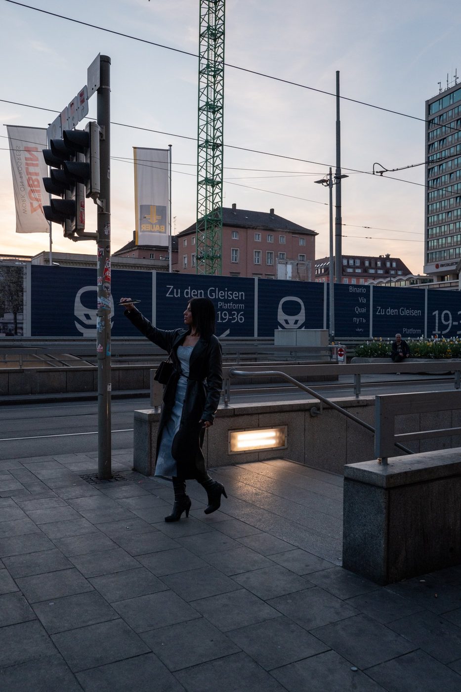 An elegant silhouette in a long dress raises her arm in the dusk light, Munich
