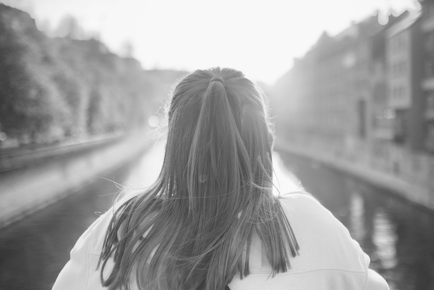 Silhouette from behind with long hair facing the light of a canal, Namur