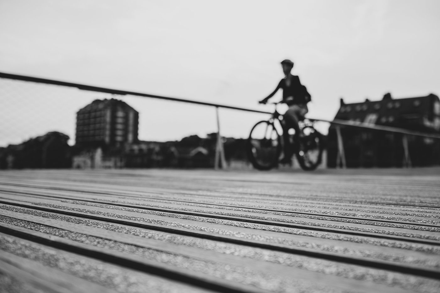 Cyclist in silhouette on a bridge, wooden slats in the foreground, Namur