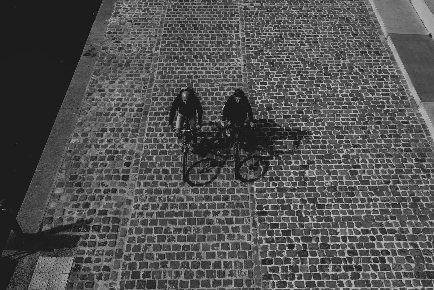 Low-angle shot of a passer-by's legs in printed trousers, behind a wire fence, Namur