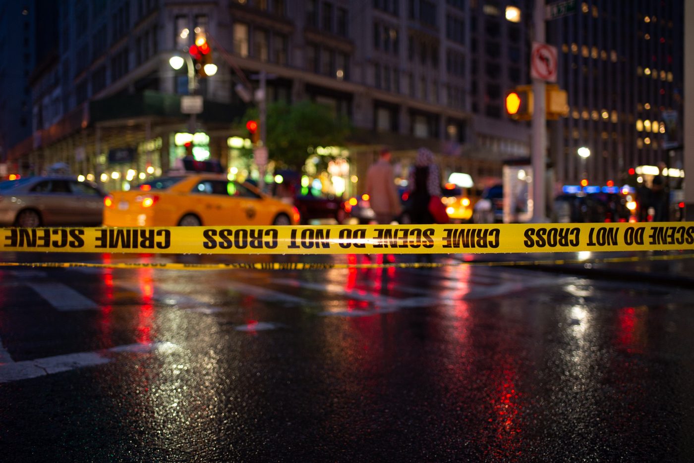 Crime scene tape in the foreground in front of a busy avenue at night, New York