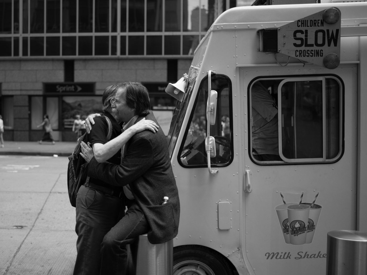 Affectionate embrace between two men in front of an ice cream truck, New York