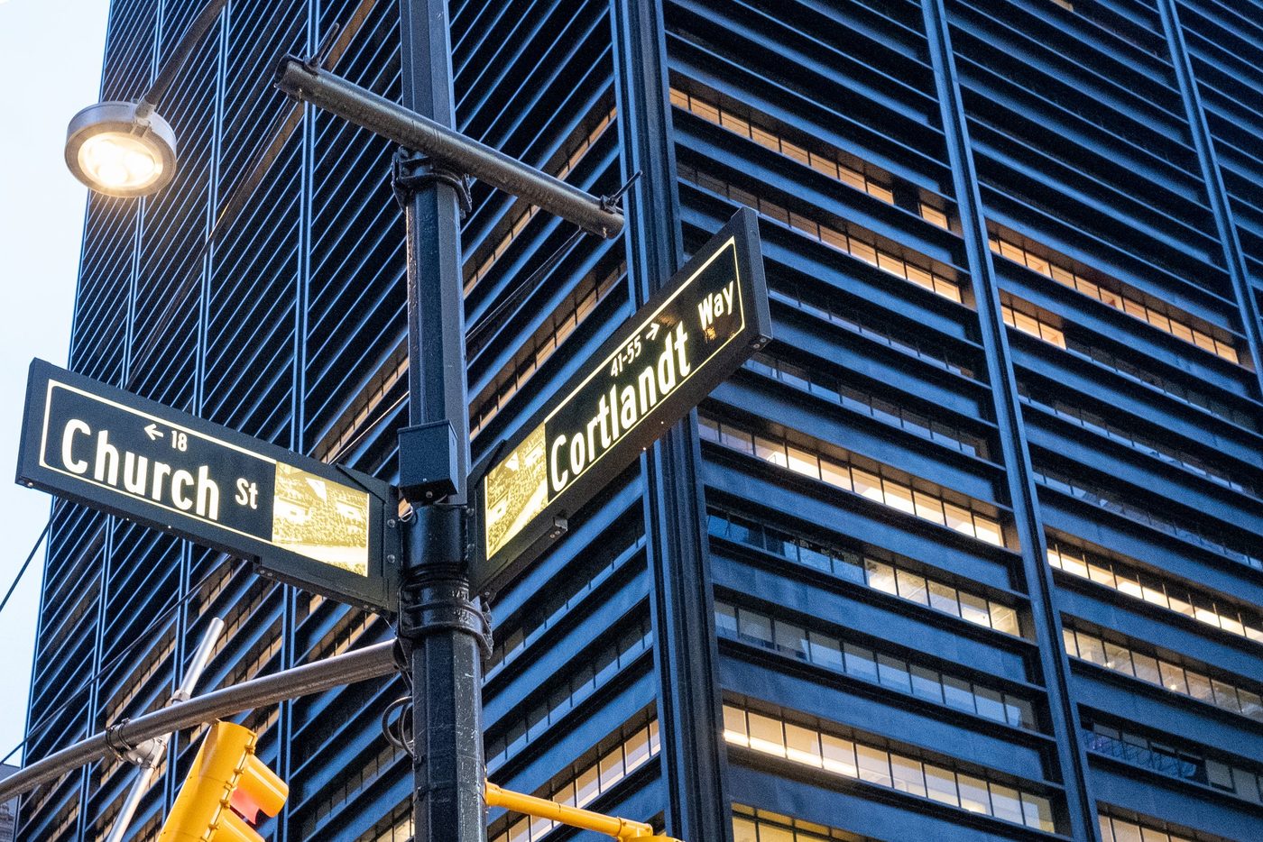 Church Street and Cortlandt Way signs in front of a glass facade at dusk, New York